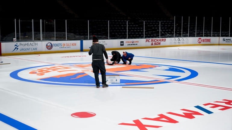 Coliseum workers paint the Islanders logo onto the ice Wednesday...