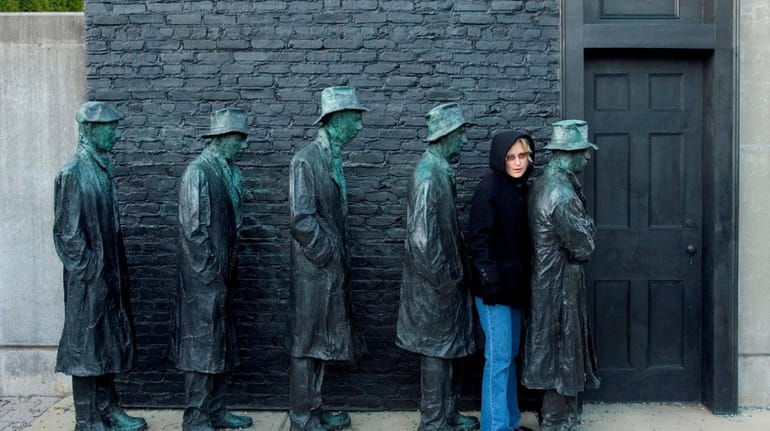 A visitor interacts with a  Great Depression bread line sculpture.