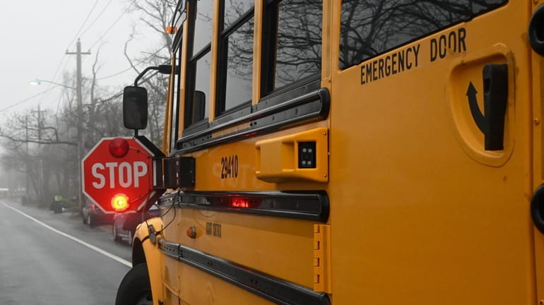 A stopped school bus, with sign out and lights flashing