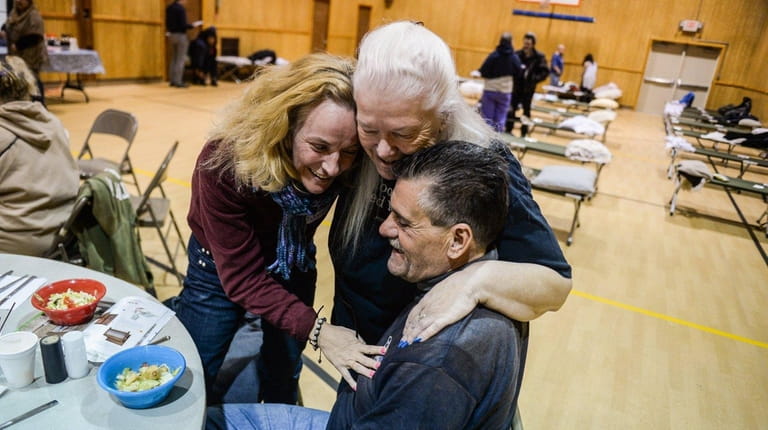 Volunteer Kathy Peterman, center, hugs Michele Del Perra and Tommy...