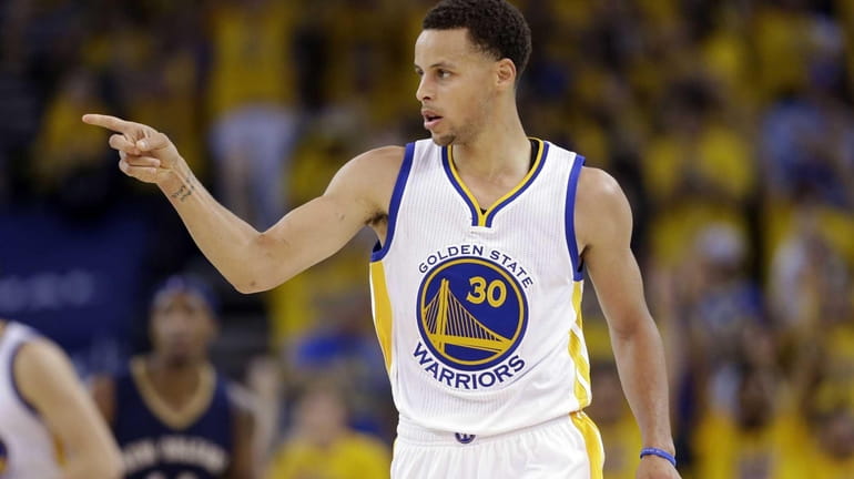 The Golden State Warriors' Stephen Curry (30) points to a...
