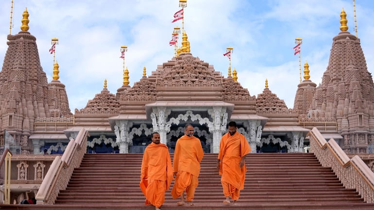 Hindu monks walk down the stairs of the first stone-built...