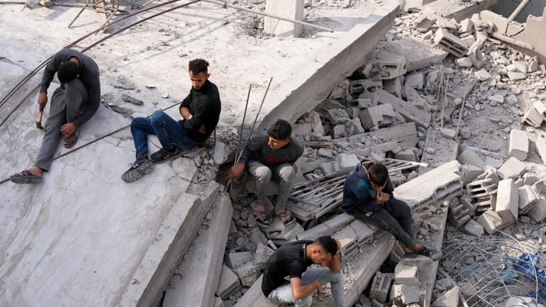 Palestinians sit by the building of the Al-Nadi family destroyed...