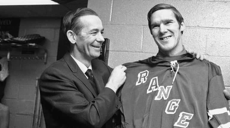 Tim Horton is measured up for a Rangers uniform by coach Emile...