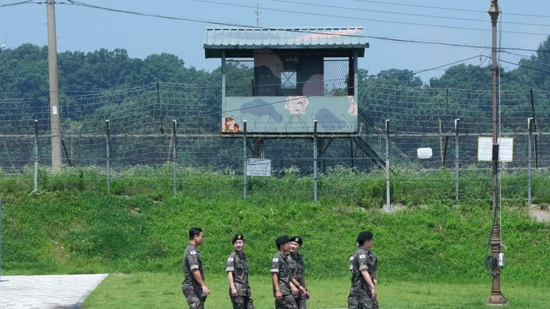 South Korean army soldiers pass by a military guard post...
