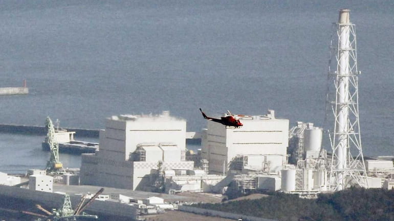 A helicopter flies past Japan's Fukushima Daiichi No.1 nuclear reactor....