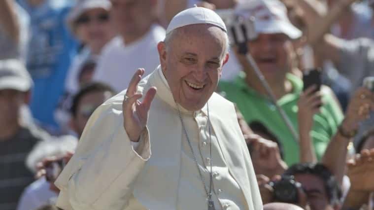 Pope Francis waves as he arrives for his weekly general...