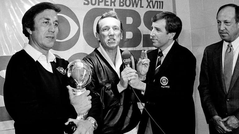 Oakland Raiders coach Tom Flores clutches the Super Bowl trophy...