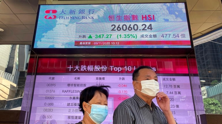 People walk past a bank's electronic board showing the Hong...