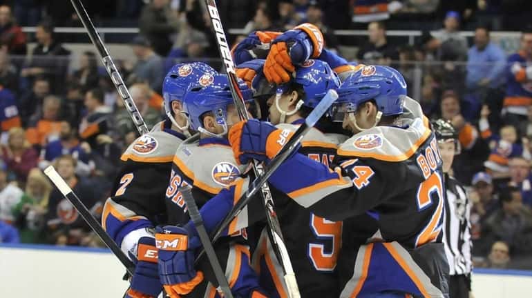 John Tavares, center, is mobbed by his Islanders teammates after...