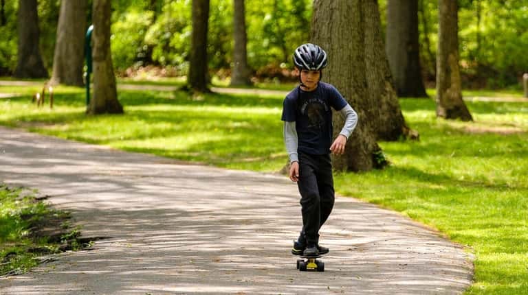 Artemi Takshait, of Forest Hills, practices his skateboarding skills on...