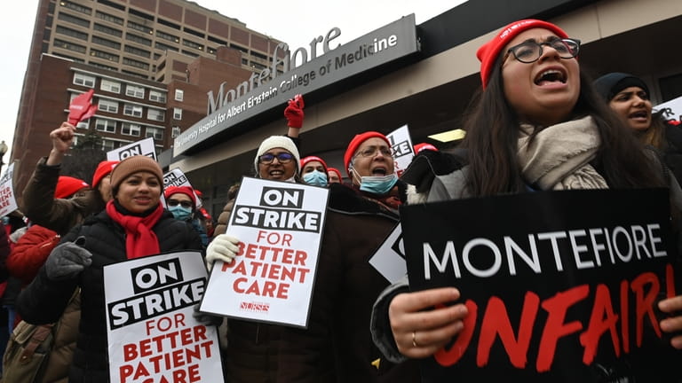 Nurses hold protest signs with demands during a strike at...