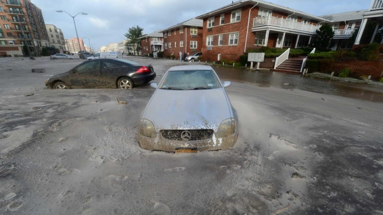 Cars are left embedded in sand left after a storm...
