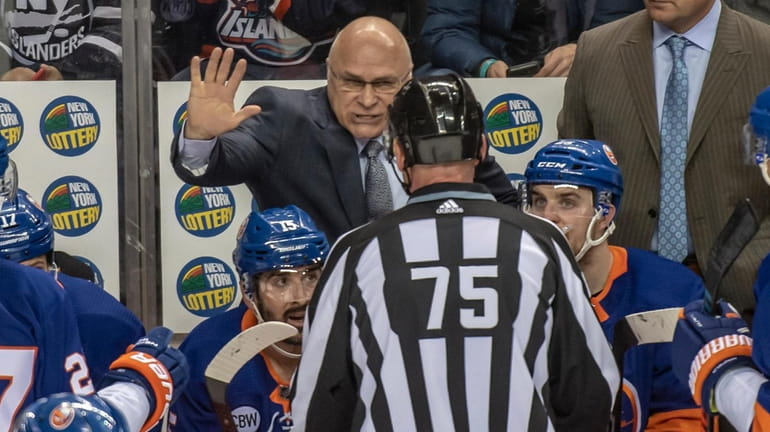 Islanders head coach Barry Trotz talking with referee Derek Amell...
