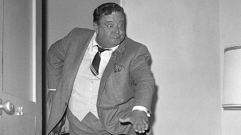 Comedian Jackie Gleason clowns for photographers after a news conference...
