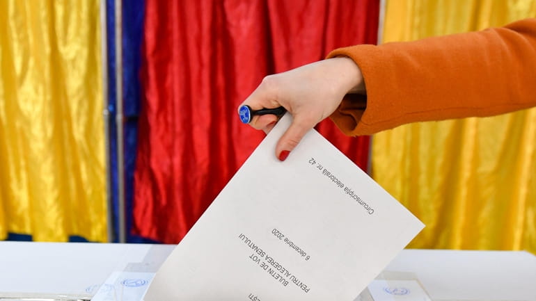A woman casts her vote in Romania's legislative election, in...