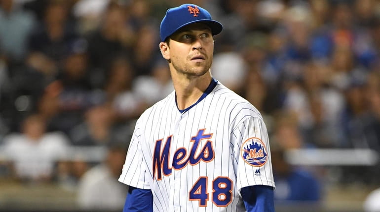 Jacob deGrom looks at the scoreboard as he exits and...