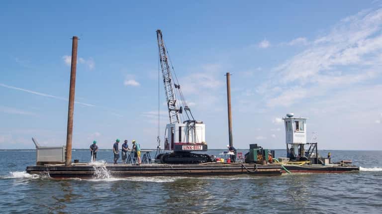 Workers dredging from a barge during the shellfish survey conducted by...
