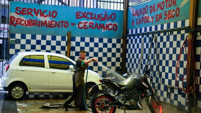 A worker washes a motorcycle at an ecological carwash in...