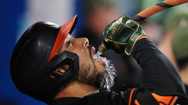 Baltimore Orioles' Anthony Santander drinks from a hose as he...