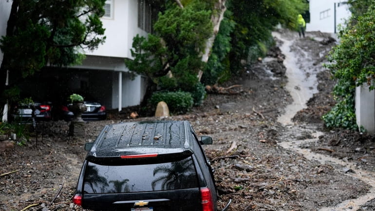 An SUV sits buried by a mudslide, Monday, Feb. 5,...