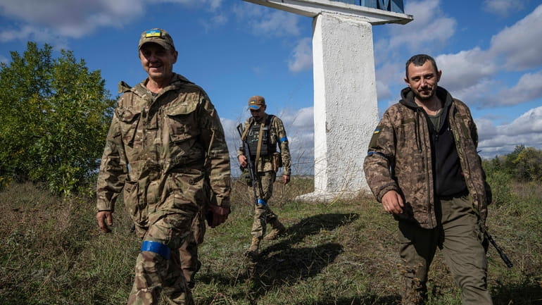 Ukrainian soldiers walk to their position in the recently retaken...