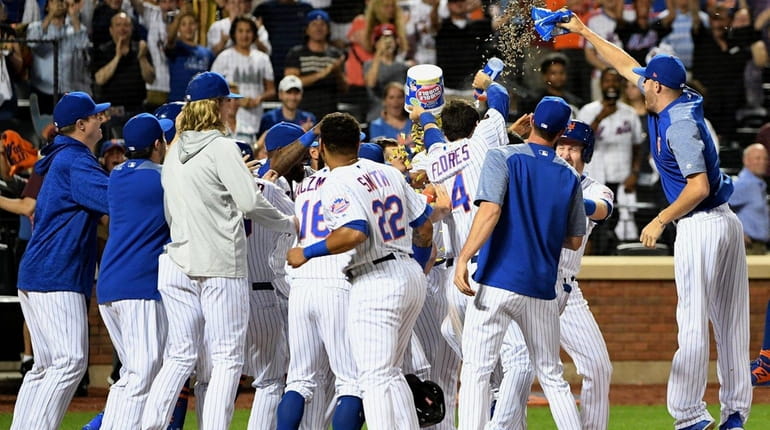 Mets players mob Jose Bautista at home plate after his...