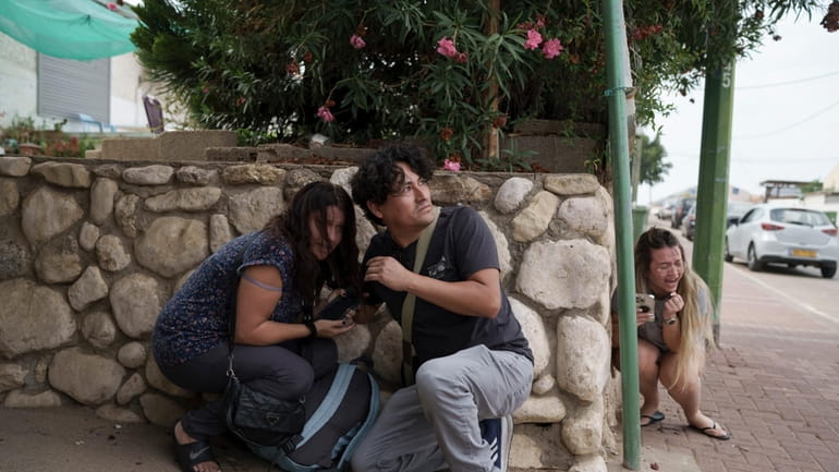Israelis take cover from the incoming rocket fire from the...