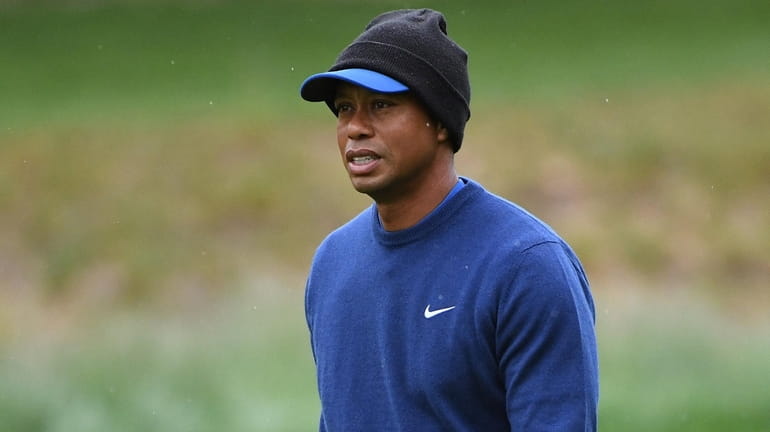 Tiger Woods looks on from a fairway as it rains...