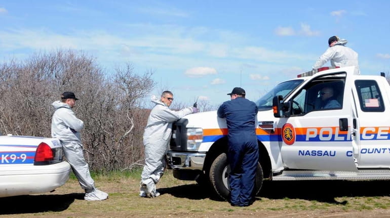 Nassau County Police pause near a wooded area along the...