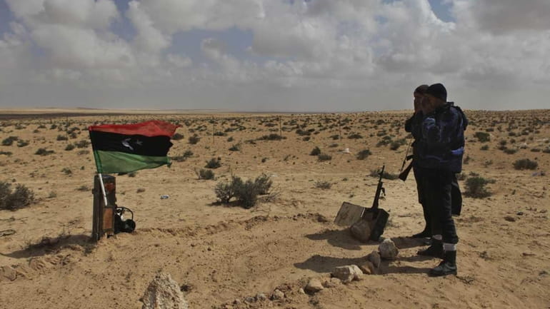 Libyan rebels pray near the a graves of their fellow...