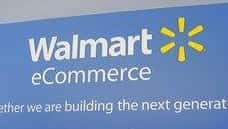 Walmart employees walk past a sign in the lobby at...