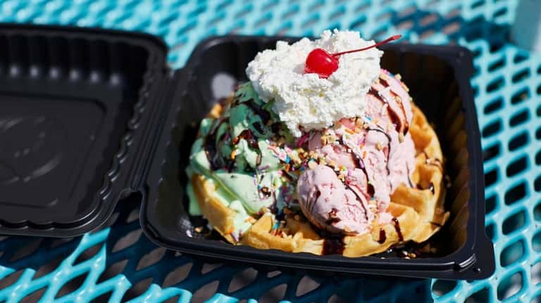 A waffle topped with mint chocolate chip ice cream, strawberry...
