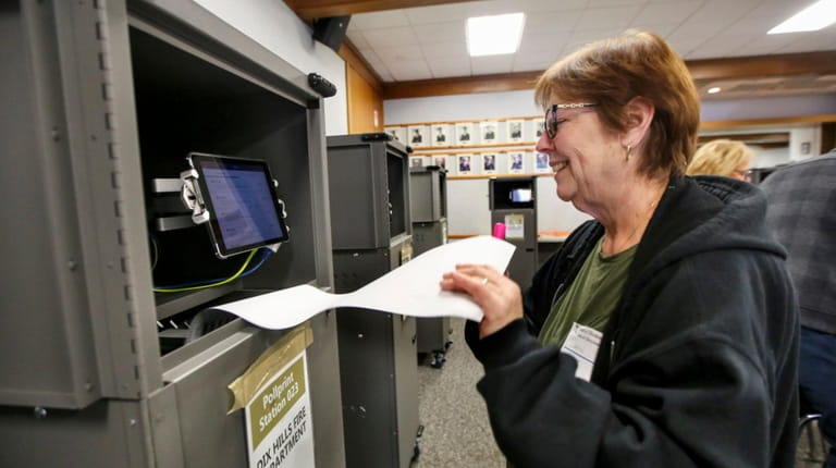 Election worker Lynda Lupoletti grabs a ballot from a printer...