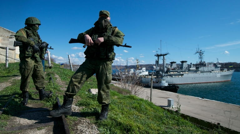 Russian soldiers guard a pier where two Ukrainian naval vessels...