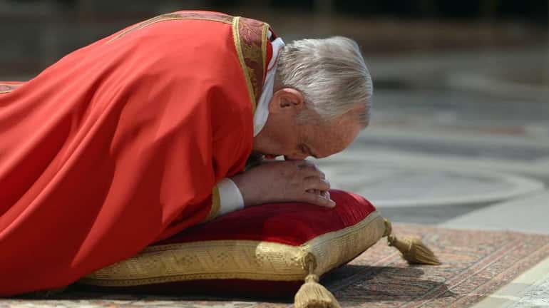 Pope Francis lies on the ground during the Lord’s Passion...