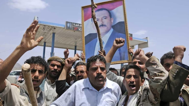 Supporters of Yemeni President Ali Abdullah Saleh hold up his...