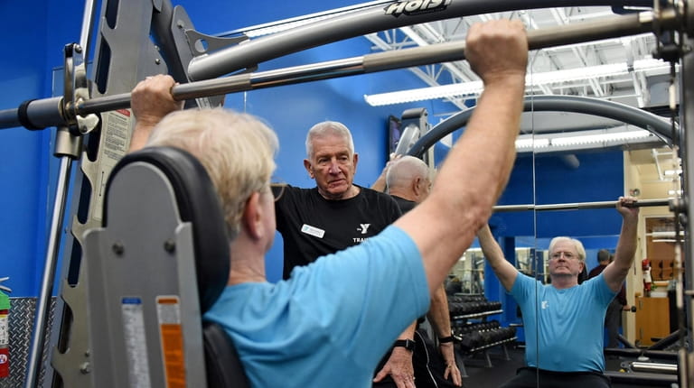 Personal trainer Wayne Ruben of Northport, center, works with his client...