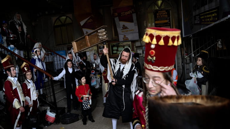 Jewish ultra-Orthodox men and children, some wearing costumes, celebrate the...
