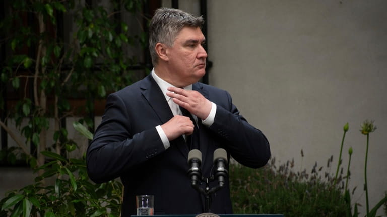 Croatia's President Zoran Milanovic adjusts his tie at a press...