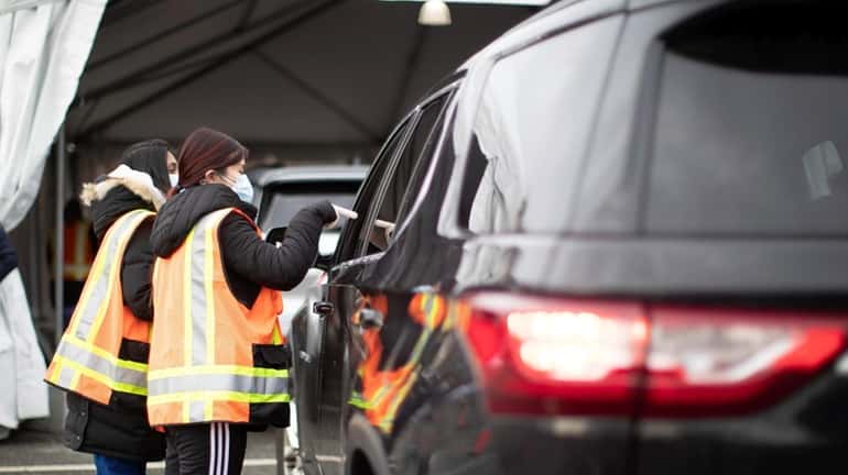 Technicians assist people in their cars on Tuesday at a...
