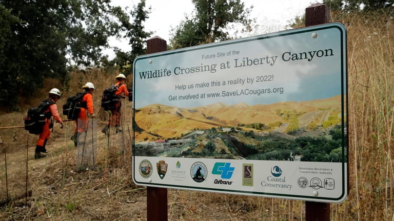 A fire crew walks past a sign at a proposed...