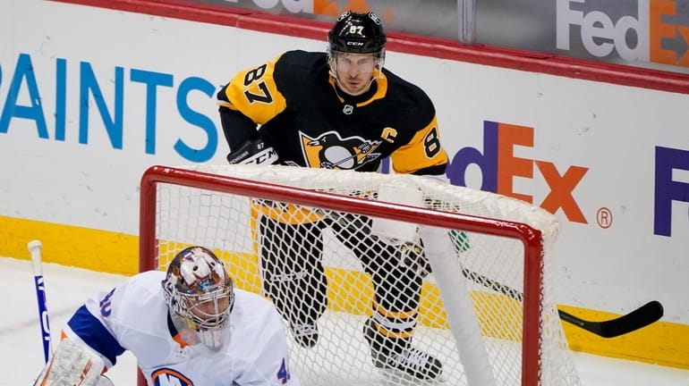 Pittsburgh Penguins' Sidney Crosby skates behind the net protected by Islanders...