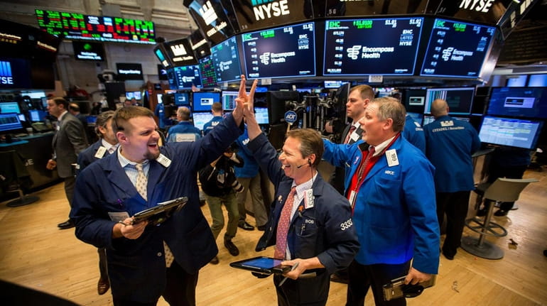 Traders react after the closing bell on the floor of...