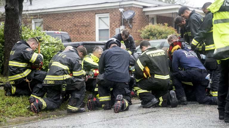 Firefighters and rescue crew pray in front of a home...