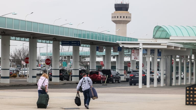 Travelers walk towards the main terminal at MacArthur airport in...