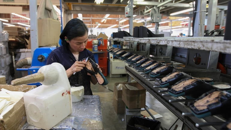 A woman works in a shoe maquiladora or factory in...