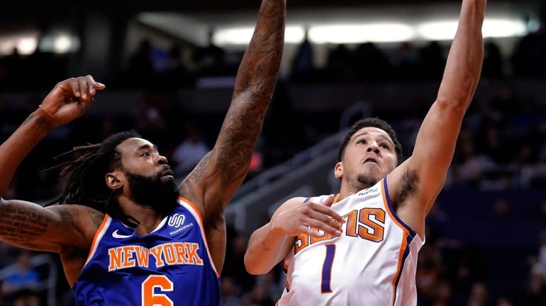 Suns guard Devin Booker shoots next to Knicks center DeAndre...