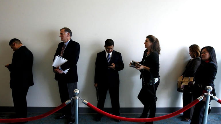 Job searchers wait in line during a career fair on...