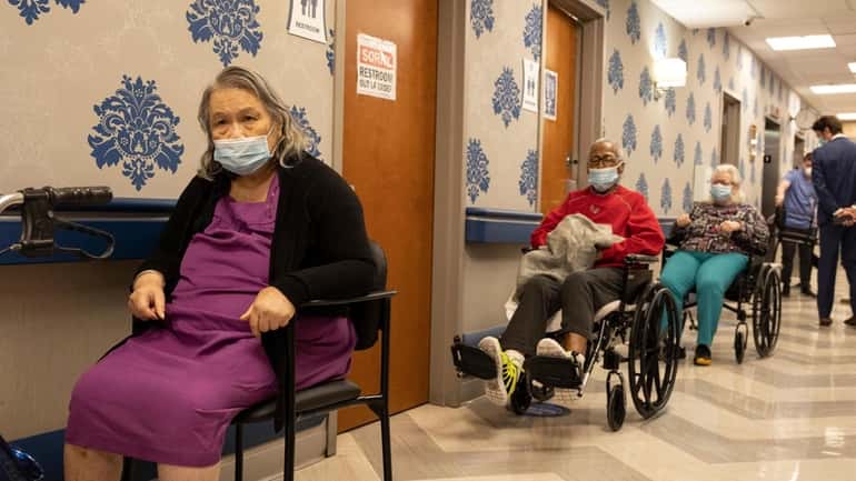 Nursing home residents wait on line to receive a COVID-19...